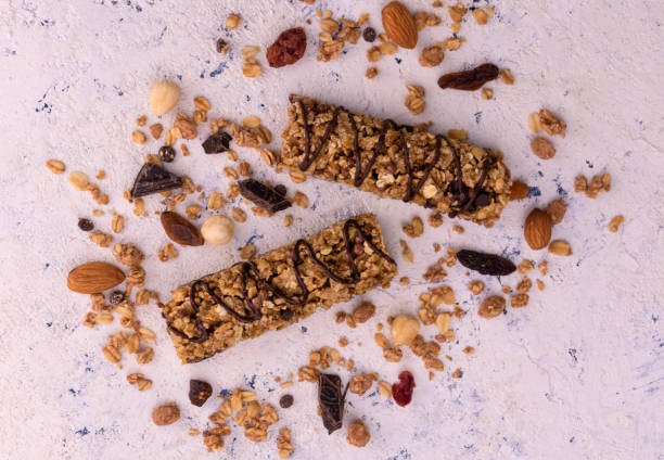 barras de granola con chocolate sobre fondo de textura blanca. tendido plano. - protein bar cereal oat cranberry fotografías e imágenes de stock