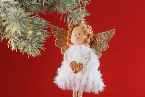 istock White angel toy on a Christmas tree on a red background. 1358572809