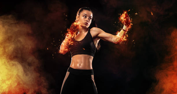 Woman boxer on black background in the fire. Boxing and fitness concept. stock photo