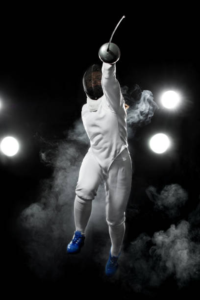 istock Fencing athlete player with rapier on the black background 1358578341