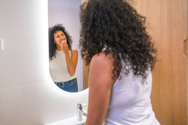 istock Hispanic Woman Brushing Her Teeth In Front Of Mirror 1358580836