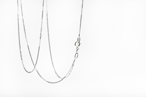 Silver chain hanging on a white background