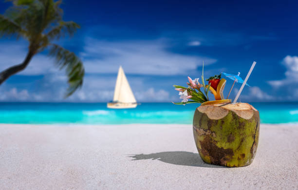 istock Coconut drink on a sandy beach with sailboat 1358581275