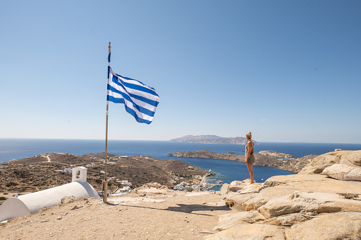 She looks at the beautiful traditional greek town on the hill on Ios Island, Greece.