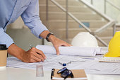 The engineer is drafting the planning structure. with architect equipment and architectural blueprints at the desk, coffee