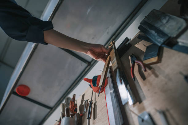 istock low angle view Asian Chinese Female Carpenter picking up l shape ruler and compass from workbench rack 1358583703