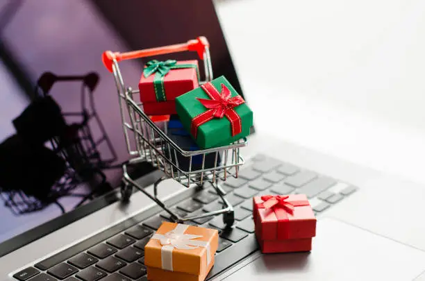 Photo of Black friday mini shopping bags in cart on the keyboard Online shopping ideas and home delivery services during the holidays.