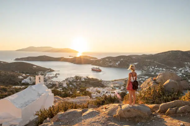 She looks at the beautiful traditional greek town on the hill on Ios Island, Greece.