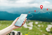 Woman hand using smart phone on top of mountain with navigator location point. Amazing Carpathians landscape background banner panorama with hills, clouds