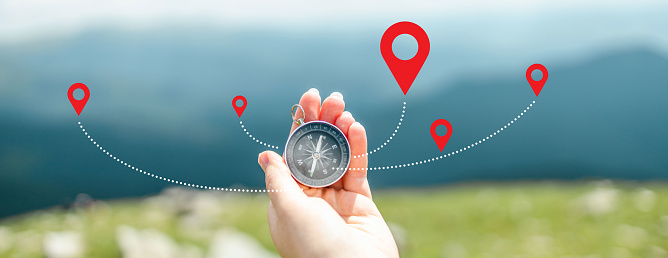 Traveler holding compass in hand for searching direction outdoor. Person use compass to find location. Mountain progression path.