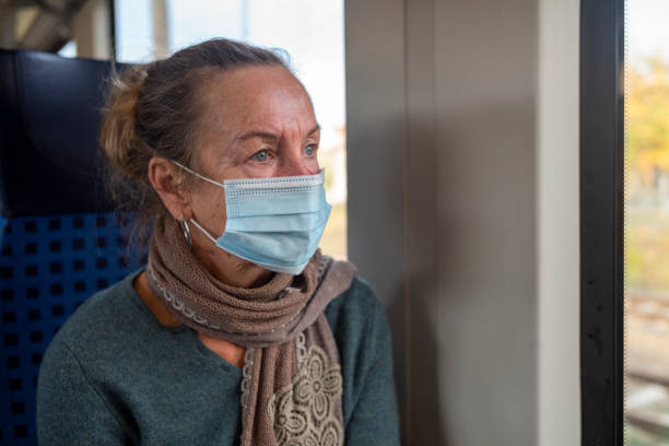 istock Covid-19 elderly woman with protective mask on the train 1358590674