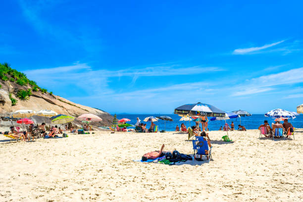 Niteroi, Brazil - December 10, 2021: People under umbrellas in the sand of Sossego Beach. This is a famous place and tourist attraction in the Rio de Janeiro State.
