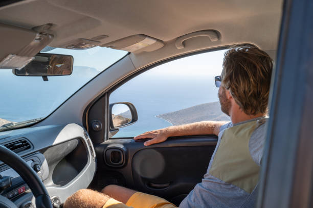 istock Young man inside a car looks at view, road trip concept 1358598796