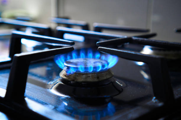 Kitchen stove grate on a burner fuelled by combustible natural gas or syngas, propane, butane. Blue flame from gas hob produce greenhouse gas emissions. Cooker as heater. Wastage of natural resources la llama azul de la placa de gas produce emisiones de gases de efecto invernadero. rejilla de la estufa de cocina en un quemador alimentado por gas natural combustible o gas de síntesis, propano, butano. cocina como calentador. desperdicio de recursos nat