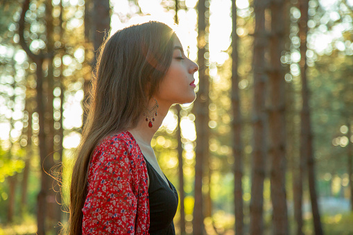 Profile view of beautiful young woman with closed eyes enjoying the sound of the woods.