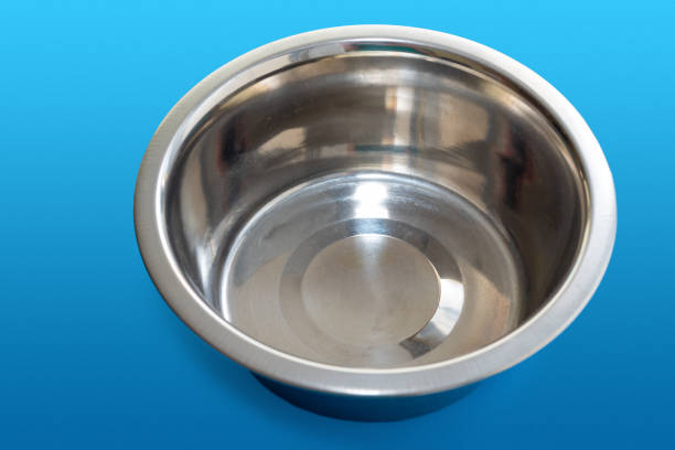 Empty round metal bowl for feeding animals on a blue background, top view.