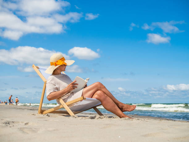 istock Woman relaxing on beach reading book 1358606622