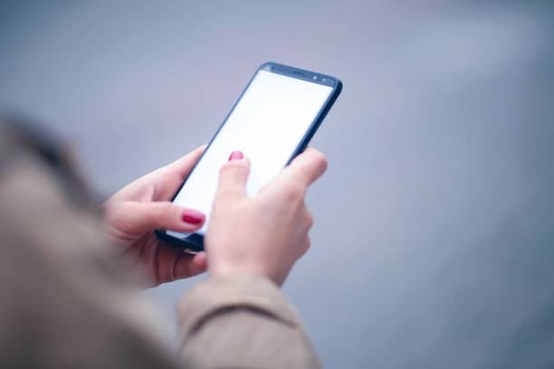 istock Woman hand holding black mobile phone isolated on white clipping path inside 1358608792