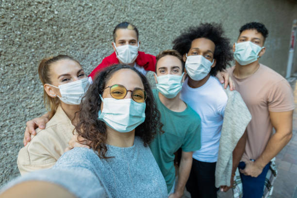 istock Friends are looking at camera and smiling with masks 1358609281