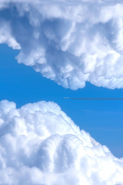 istock Plane among large white clouds.Transportation and Environment concept. 1358611362