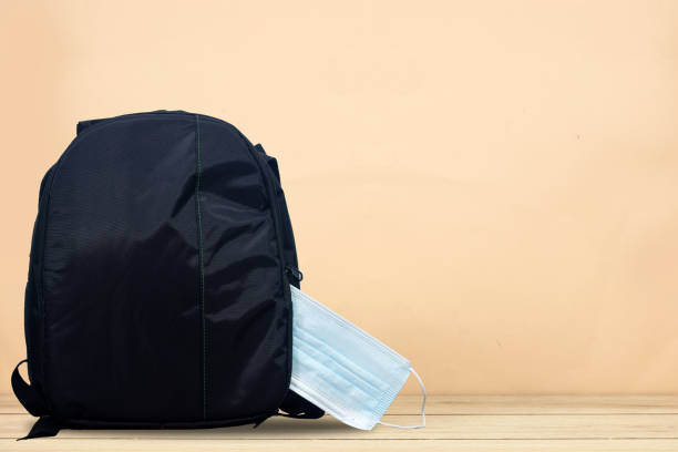 istock COVID-19 prevention, back to school and new normal concept.School backpack with school supplies and medical face mask on wood table 1358612930