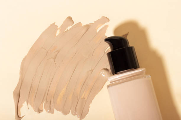 istock Foundation in a glass bottle smeared on the table. Face corrector on beige background with copy space. Packaging mockup with copy space 1358613812