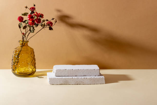 istock Background with geometric shapes made of concrete for cosmetic products. Rectangular podiums, glass vase with dried flowers and shadows on a beige background. Blank mockup for product 1358613814