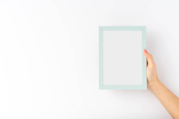 istock Woman’s hands holding empty photo frame on white background with copyspace. Mock up 1358616930
