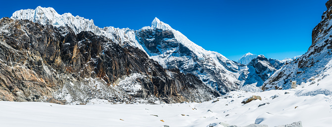 60 MPix XXXXL size panorama of Mount Ama Dablam - probably the most beautiful peak in Himalayas. This panoramic landscape is an very high resolution multi-frame composite and is suitable for large scale printing. Ama Dablam is a mountain in the Himalaya range of eastern Nepal. The main peak is 6,812  metres, the lower western peak is 5,563 metres. Ama Dablam means  'Mother's neclace'; the long ridges on each side like the arms of a mother (ama) protecting  her child, and the hanging glacier thought of as the dablam, the traditional double-pendant  containing pictures of the gods, worn by Sherpa women. For several days, Ama Dablam dominates  the eastern sky for anyone trekking to Mount Everest basecamp