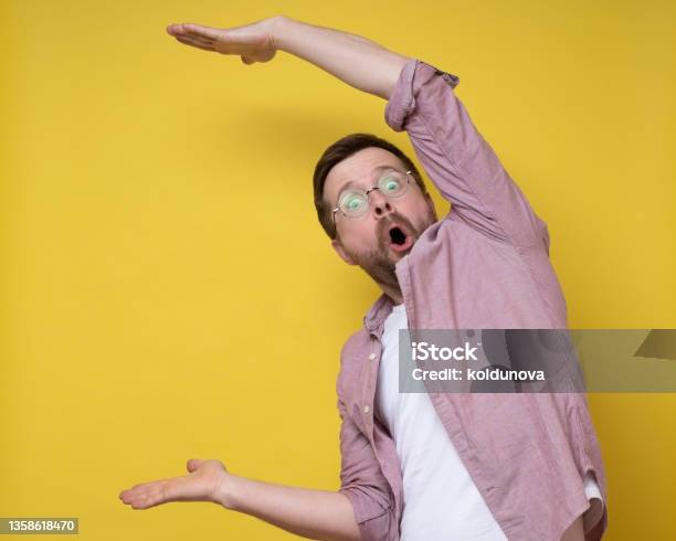 Surprised Man In Glasses Shows A Large Size With Hands He Exaggerates And Looks At The Camera In Amazement Copy Space Stock Photo - Download Image Now
