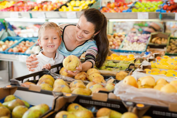 小さな男の子と店で梨とリンゴを買う陽気な母親 - two pears ストックフォトと画像