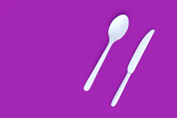 istock White spoon and knife on violet background. Top view. Copy space. 3d render 1358619857