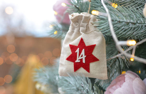 antecedentes navideños. calendario de adviento en forma de bolsas ecológicas colgadas en un árbol de navidad bellamente decorado. regalos y tareas navideñas - advent calendar christmas number number 14 fotografías e imágenes de stock