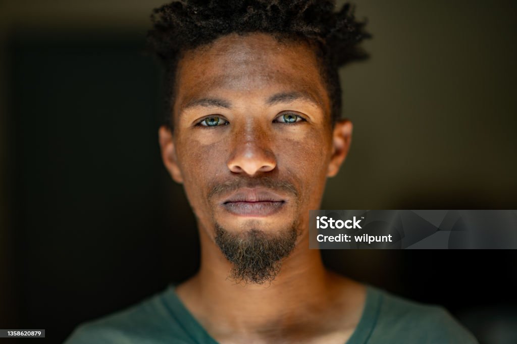 Close up Headshot Portrait of young mixed race male face with green eyes facial hair and rasta hair Portrait Stock Photo