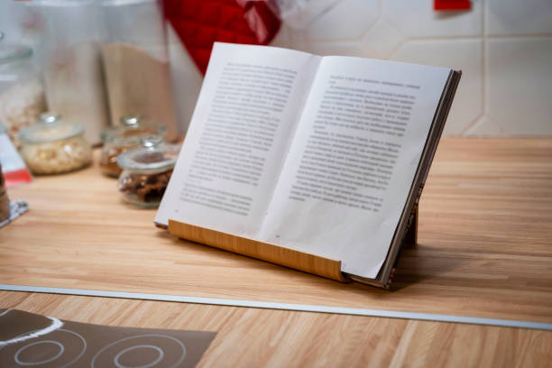an open book in a stand on the kitchen table, storage jars, kitchen utensils