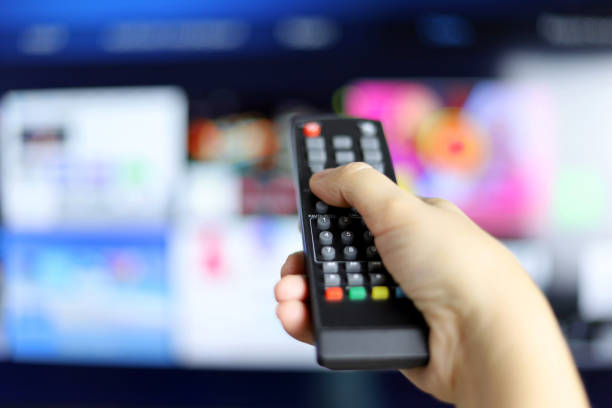 Female hand with remote controller on smart TV screen background stock photo