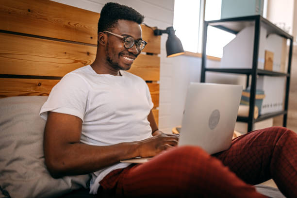 istock Man sitting on bed working on laptop 1358626894