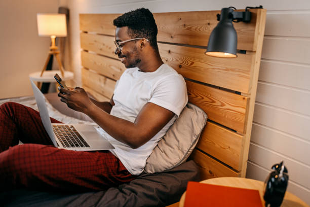 istock Man using laptop and smart phone in bed 1358626913