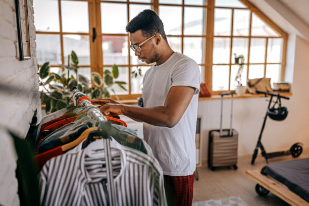 istock Man selecting clothes from rack at home 1358627230