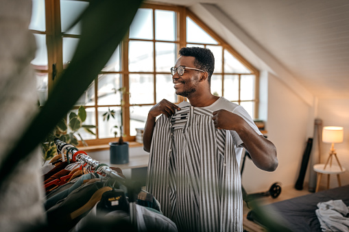 Man selecting clothes from rack at home