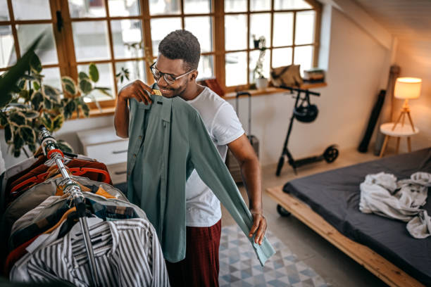istock Man selecting clothes from rack at home 1358627402