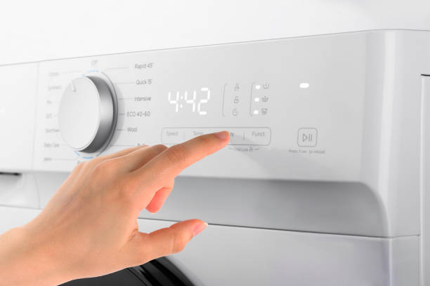 istock Young woman or housekeeper select the program on washer 1358628092