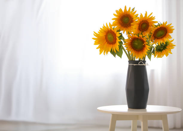 istock Vase with beautiful yellow sunflowers on table in room, space for text 1358630650