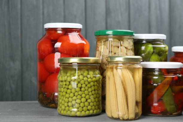 istock Glass jars with different pickled vegetables on grey wooden background 1358630888