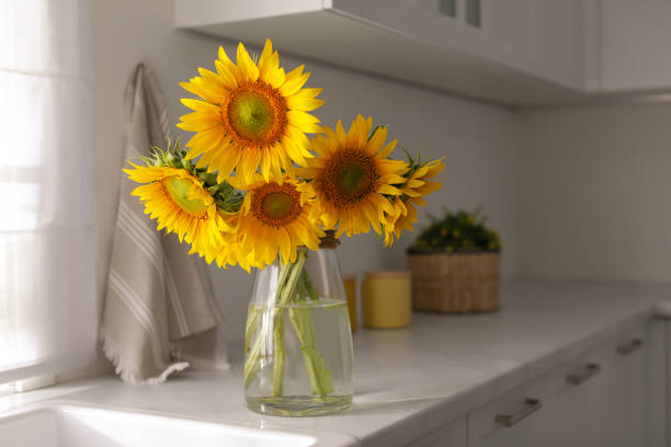 istock Vase with beautiful yellow sunflowers in kitchen, space for text 1358631198