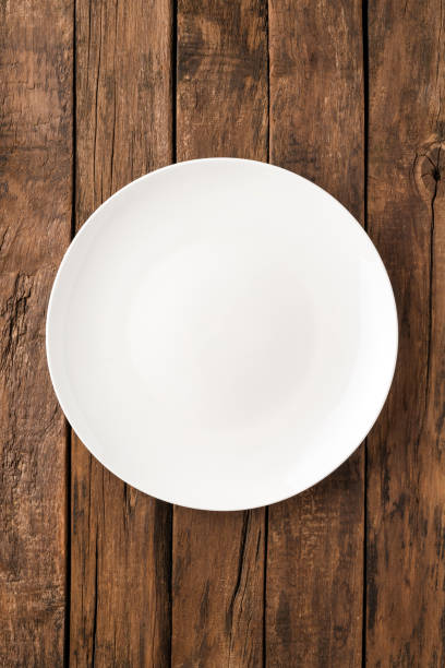 istock Overhead shot of blank white dish on rustic wooden table. Close up 1358632024