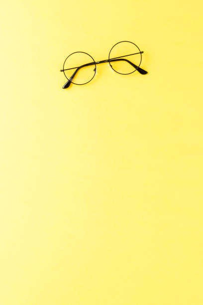 istock Round eyeglasses on yellow background with copyspace. Top view 1358633355