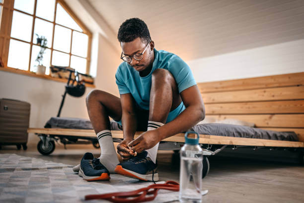 Man wearing shoes preparing for workout Young fit and healthy men wearing shoes while getting ready and preparing for home workout in the morning getting dressed stock pictures, royalty-free photos & images