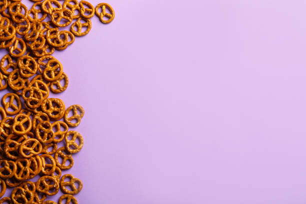 istock Delicious pretzel crackers on violet background, flat lay. Space for text 1358634096