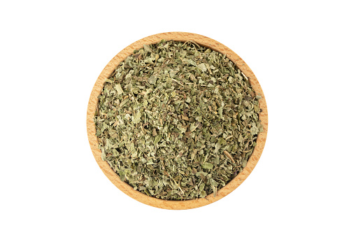 Dried Lemon balm (Melissa officinalis) herb in wooden bowl isolated on white background.
